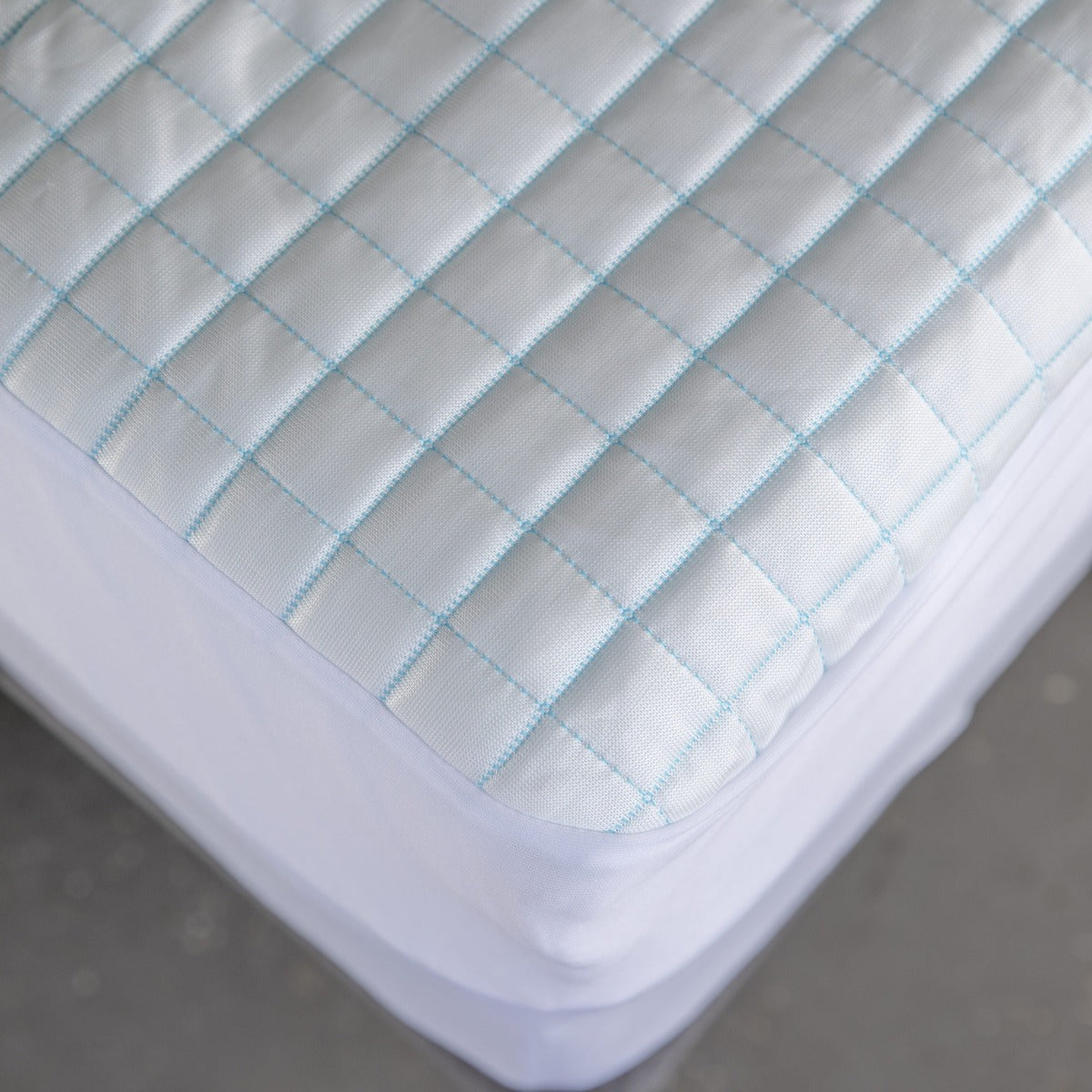 Close-up overhead view of the MLILY Cooling Ice Fiber Mattress Protector, highlighting the blue line design that demonstrates its cool-to-the-touch material. The intricate fabric detail is visible, showing the cooling effect.