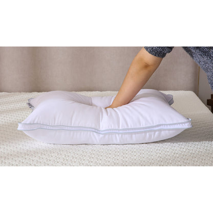 MLILY AirCell Classic pillow laying on a mattress with someone pressing down on the pillow inside a bedroom, demonstrating its supportive and cooling features.