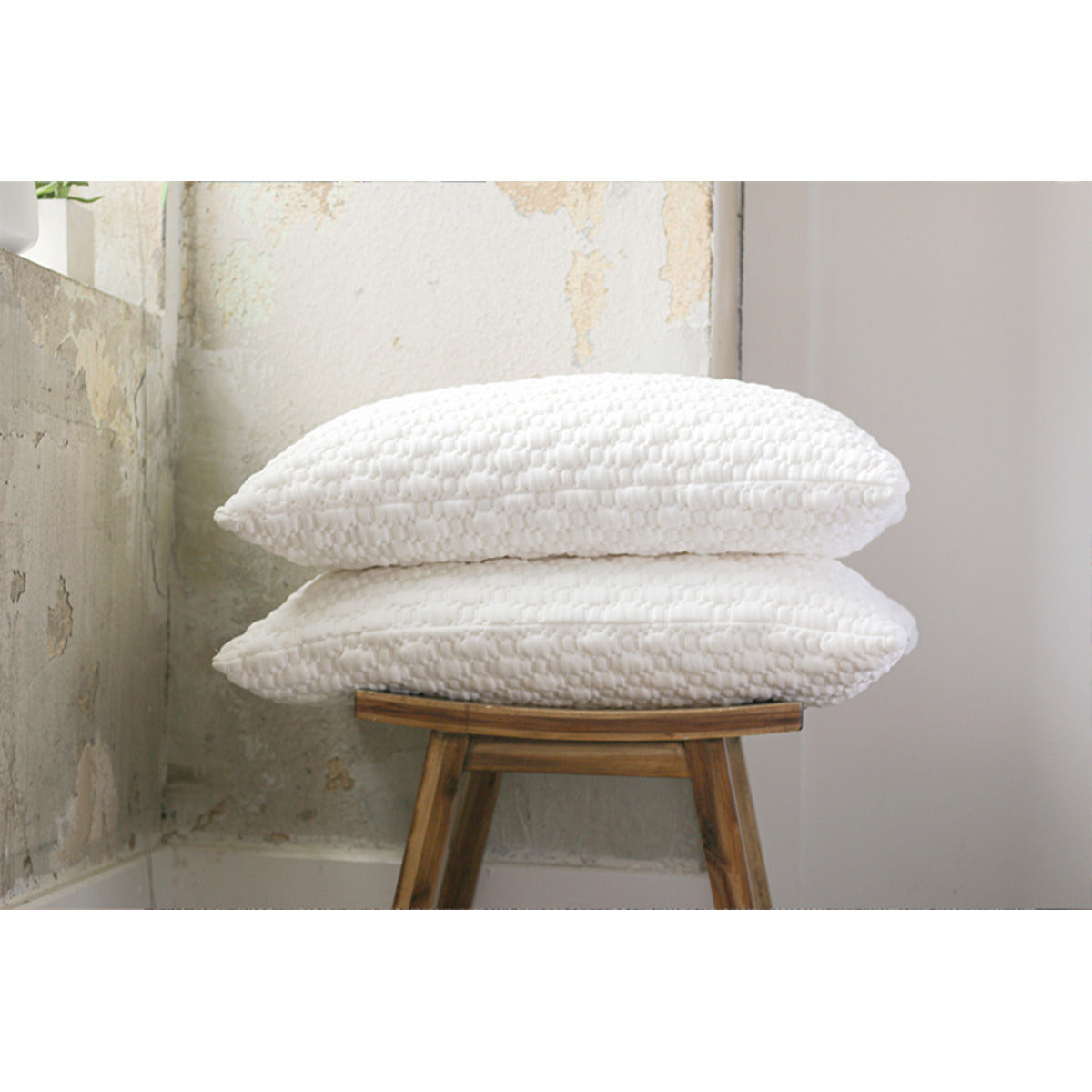 MLILY Harmony Classic Pillows stacked on top of each other, underneath the pillows is a wooden platform surface, inside of a room.