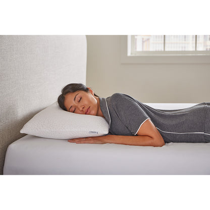 MLILY Harmony Cool Pillow at the head of the mattress, with a woman sleeping on the pillow while on her stomach, showing how the pillow can improve your sleep, mattress on top of a platform bed frame, inside of a bedroom.