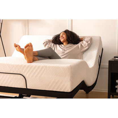 MLILY MS300 Adjustable Base with a mattress on top, head and foot parts raised, woman laying on the mattress in a relaxed position, corner view, inside a decorated bedroom.