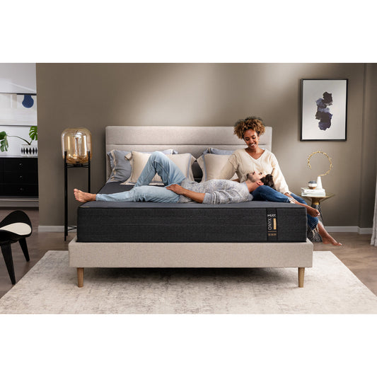 MLILY ONYX Hybrid Firm 12-inch Mattress on platform bed frame, man lying his head on a woman's lap, both smiling at each other, decorated bedroom, a few pillows at the head of the mattress.