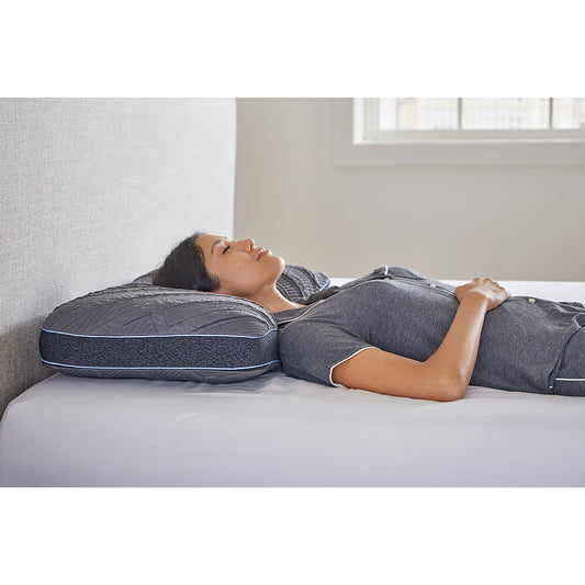 MLILY PowerCool Pillow on a mattress with a platform bed frame, inside a decorated bedroom, with a woman sleeping comfortably on her back, supported at the head, neck, and shoulders, staying cool through airflow from the base’s built-in fans.