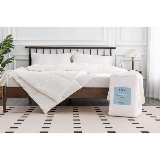 MLILY Soft Washed Down Alternative Comforter in white, spread across a bed with shams covering two pillows at the head, packaging placed at the corner foot of the bed to compare appearance before and after use, decorated bedroom.