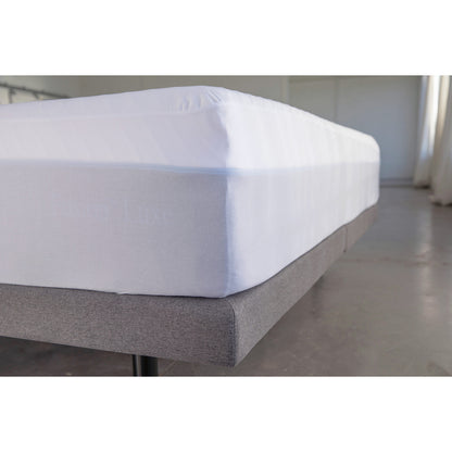 MLILY Tencel Fabric Mattress Protector fitted on a mattress corner like a sheet, on a platform base in a warehouse showroom, showcasing how it preserves your mattress investment.