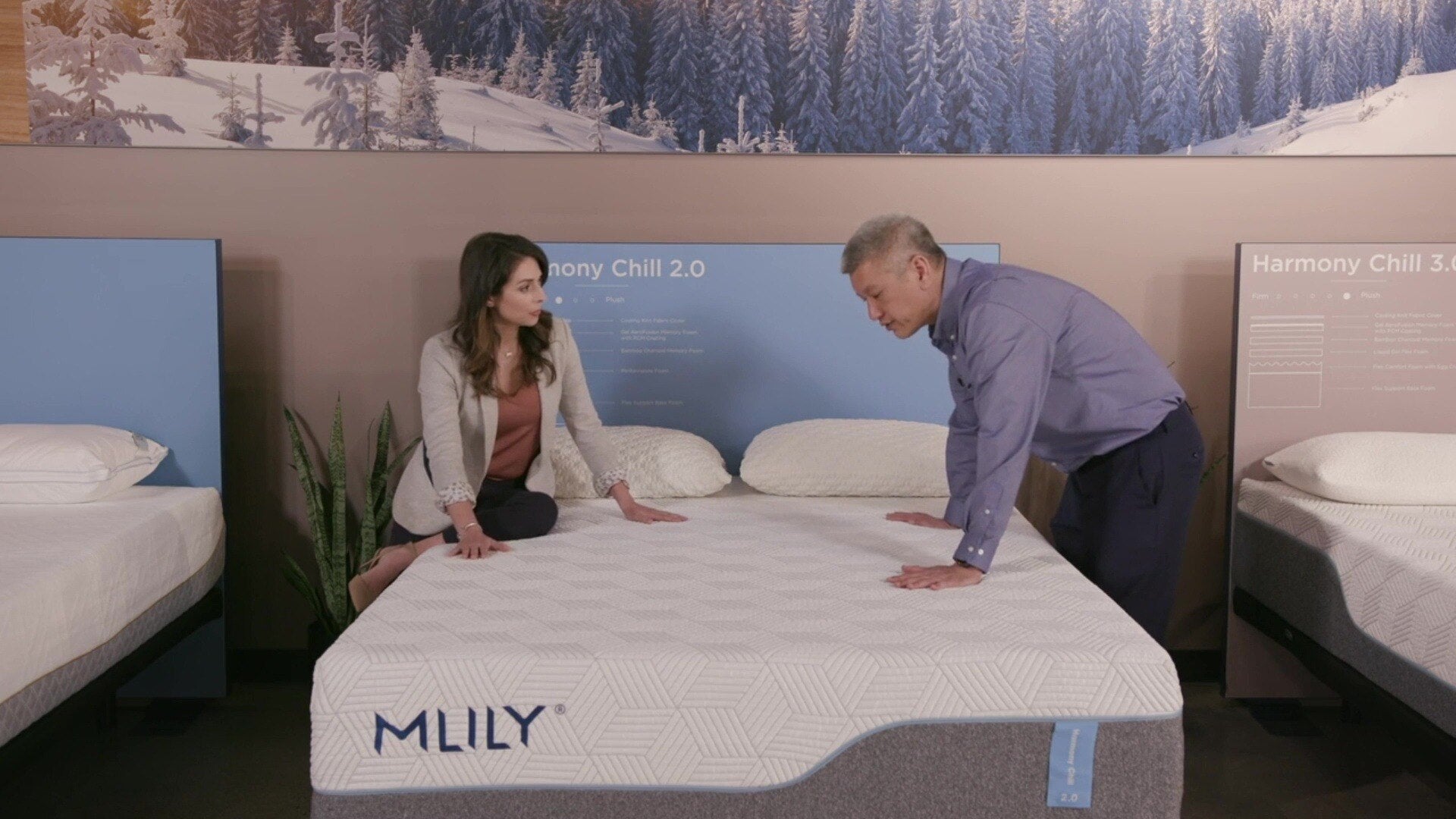 A male sales rep showcases the MLILY Harmony Chill 2.0 Memory Foam Medium 14" Mattress to a woman, highlighting its cooling cover, bamboo charcoal memory foam, breathable layers, performance foam, and PCM coating.