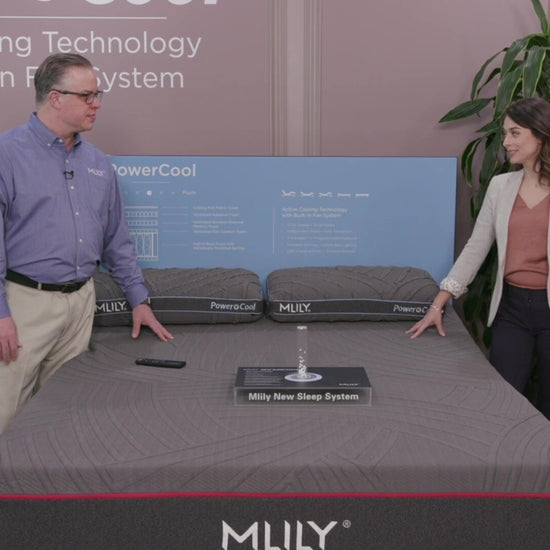 A product specialist explains the MLILY PowerCool Adjustable Base to a woman, highlighting its built-in fans with three speed settings that blow air through the mattress, offering cooling comfort along with full adjustable functionality.