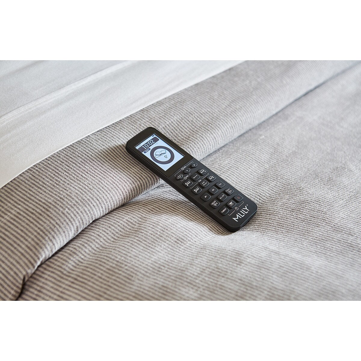 Remote control for the MLILY PowerCool Adjustable Base, resting on a bed with bedding.