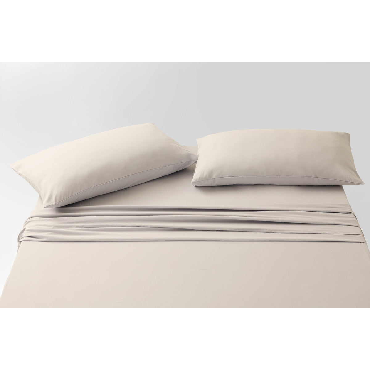 Slight aerial view of the MLILY Soft Washed Sheet Set, white background, bed fully made with two pillows at the head in a decorative layout, showcasing quality and snug fit.