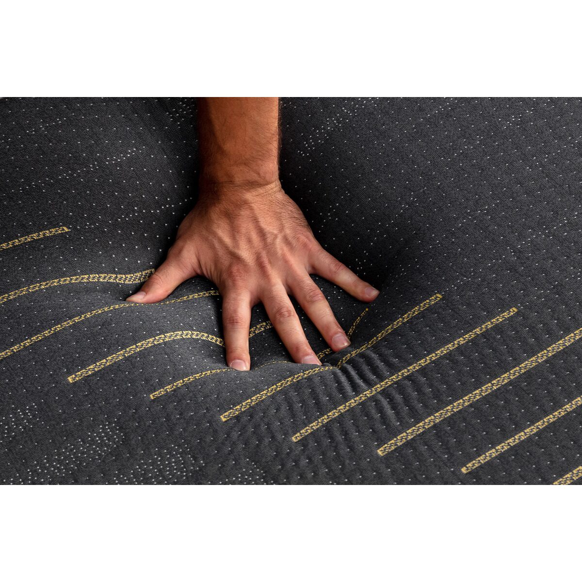 Slight overhead view showing a man's hand pressing down on the MLILY ONYX Hybrid Firm 12-inch Mattress to highlight its comfort and support, with detailed quilt design visible.