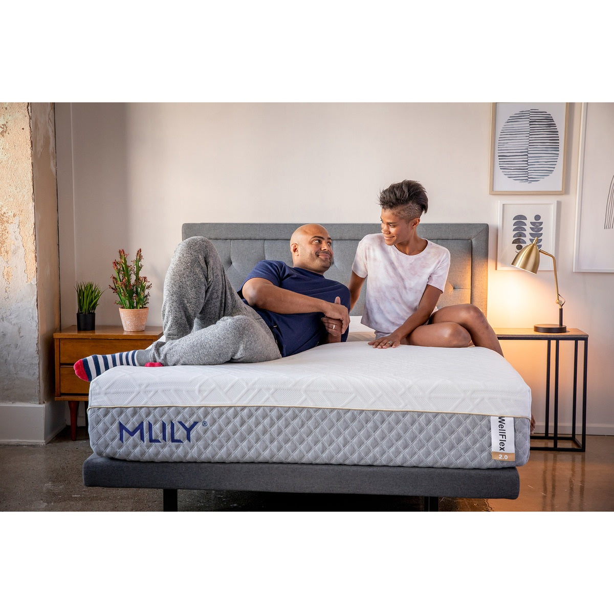 Slightly angled front view of the MLILY WellFlex 2.0 Memory Foam Medium 12" Mattress with a man and woman on the mattress, demonstrating its comfort and support, inside a decorated bedroom.