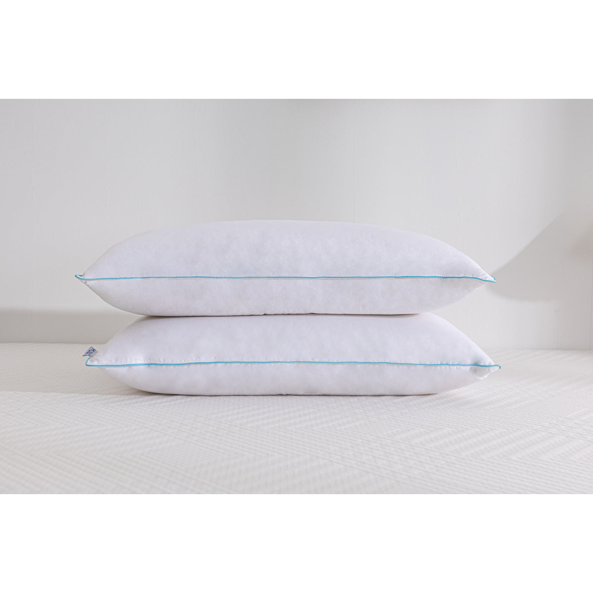 Two MLILY Ethically Sourced Down Pillows stacked on top of each other on a mattress, white background.